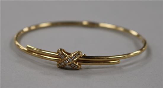 A modern Chaumet 18ct gold and diamond hinged bangle, with central X motif, gross 12.2 grams.
